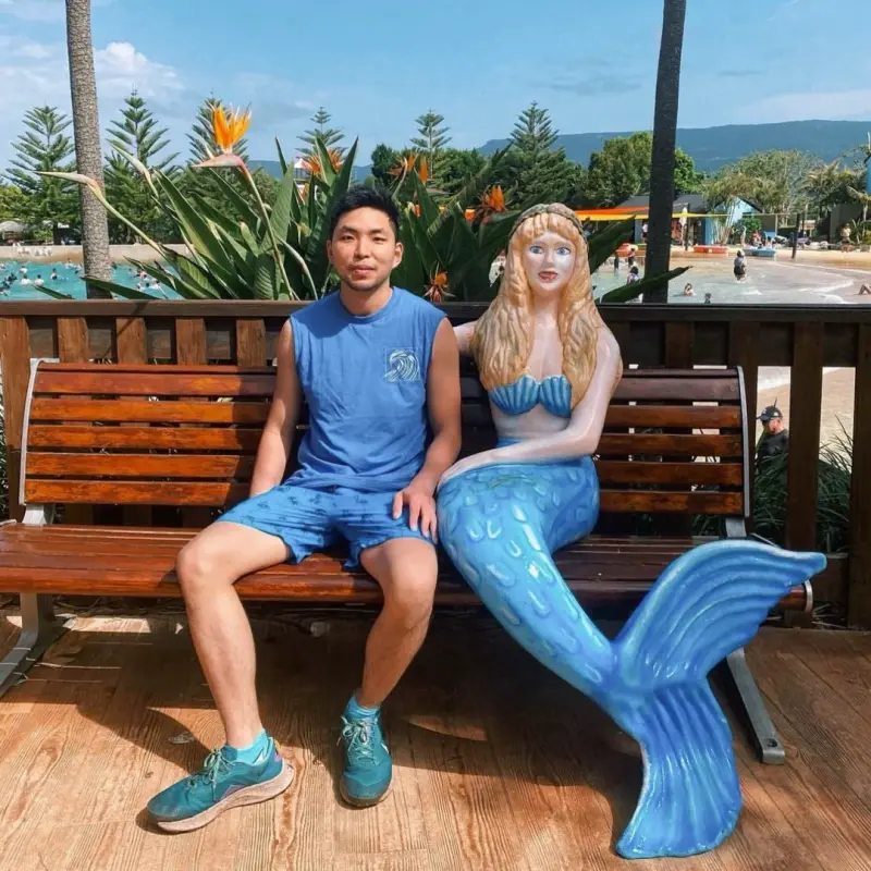 Invigorate Ability Support - 40 A participant sitting on a bench next to a performer dressed as a mermaid